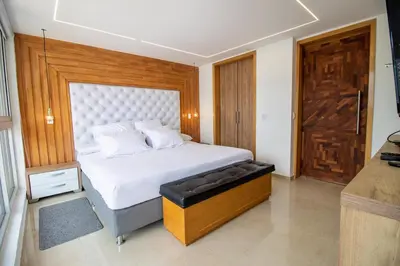 a bedroom with a white bed with a wooden door at Penthouse Stay & Relax Itagui in Itagüí