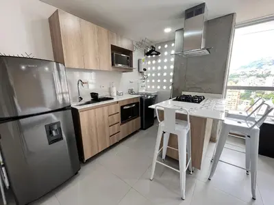 a kitchen with a stainless steel refrigerator and a table at Edificio Aiana Verde by Host Medellin in Medellín