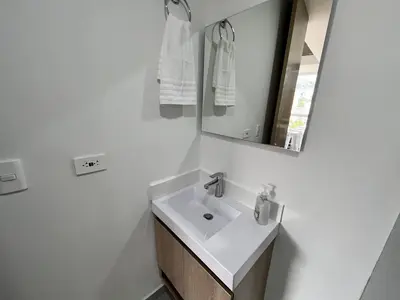 a white bathroom with a sink and a mirror at Edificio Aiana Verde by Host Medellin in Medellín