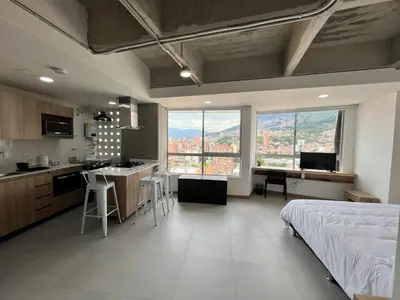 a bedroom with a bed and a kitchen with a view at Edificio Aiana Verde by Host Medellin in Medellín
