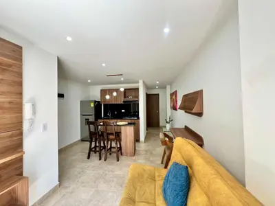 a living room with a couch and a kitchen at Laureles The NBHD apartments in Medellín