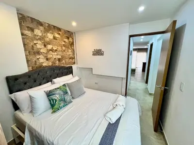 a bedroom with a large bed with a stone wall at Laureles The NBHD apartments in Medellín