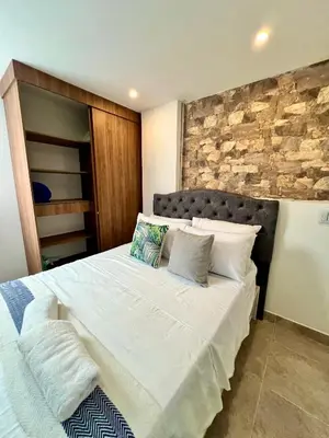a bedroom with a large white bed with a stone wall at Laureles The NBHD apartments in Medellín