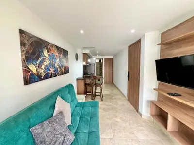 a living room with a green couch and a flat screen tv at Laureles The NBHD apartments in Medellín