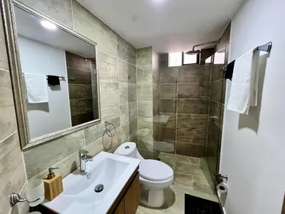 a bathroom with a sink and a toilet and a mirror at Laureles The NBHD apartments in Medellín