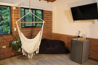 a hammock hanging in a room with a tv at Finca Hotel Recinto de la Gruta in Copacabana