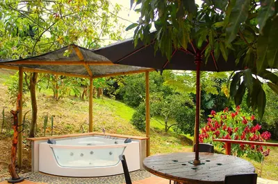 a bath tub sitting under an umbrella next to a table at Finca Hotel Recinto de la Gruta in Copacabana
