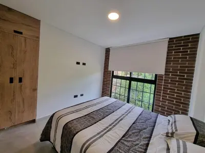 a bedroom with a bed and a brick wall at Apartment with a hot tub and a view of Guatapé lake in Guatapé