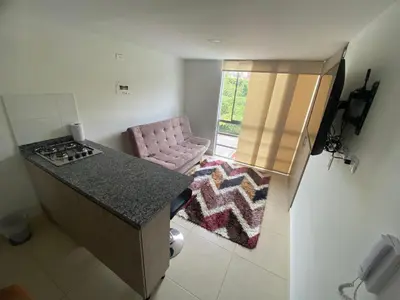 a small kitchen with a stove and a pink chair at Sector Turistico, Confort y Full Amoblado in Manizales
