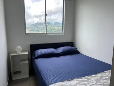 a bedroom with a blue bed and a window at Estancias confortables, amigos y familia in Manizales