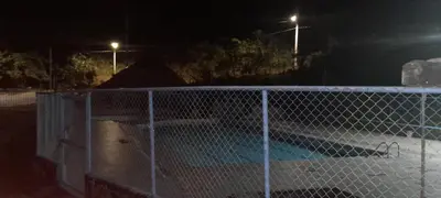 a fence in front of a swimming pool at night at Hotel Estadero Piscina EL CACIQUE GUARKAMA in Montañadentro