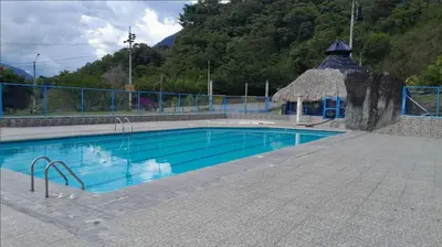 a swimming pool with a gazebo next to a mountain at Hotel Estadero Piscina EL CACIQUE GUARKAMA in Montañadentro