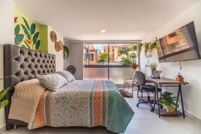 a bedroom with a bed and a desk and a television at Cozy Spring Flat in Laureles in Medellín