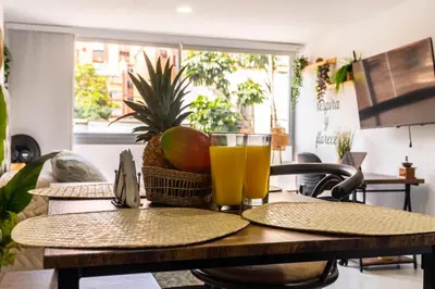 a table with a glass of orange juice and a basket of fruit at Cozy Spring Flat in Laureles in Medellín