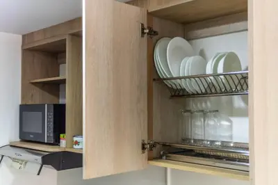 a kitchen with a cupboard with plates and a microwave at Cozy Spring Flat in Laureles in Medellín