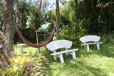 two white benches and a hammock in a garden at Casa Finca El Peñol Antioquia in El Peñol