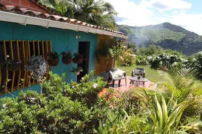 a blue house with a table and chairs in a garden at Casa Finca El Peñol Antioquia in El Peñol