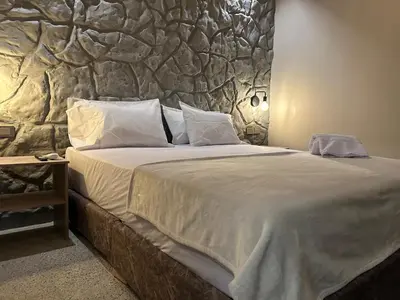 a bedroom with a large bed with a stone wall at Casa Kyros Boutique in Medellín