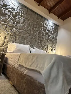 a bed in a room with a stone wall at Casa Kyros Boutique in Medellín