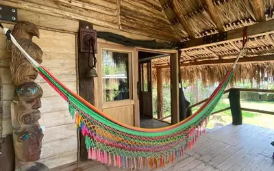 a hammock hanging from the side of a log cabin at Cabaña ecologica en el Rio Cocorna, Puerto Triunfo in Providencia