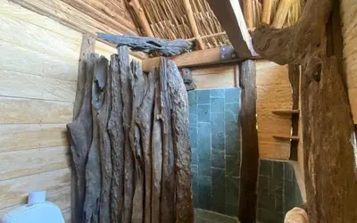 a bathroom with a wooden wall with a toilet at Cabaña ecologica en el Rio Cocorna, Puerto Triunfo in Providencia