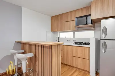 a kitchen with wooden cabinets and a white refrigerator at Aria Living 200 - Vibrant Apartment in Laureles in Guayaquil