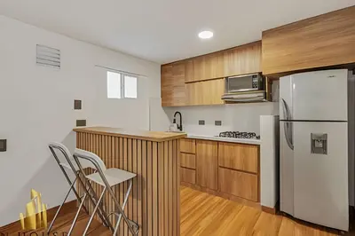 a kitchen with a white refrigerator and wooden cabinets at Aria Living 201 - Where Design and Location Shine in Guayaquil