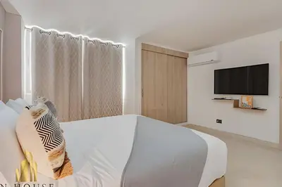 a white bedroom with a bed and a tv at Aria Living 202 - Spacious Urban Luxury Retreat in Guayaquil