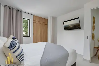 a white bedroom with a white bed and a television at Aria Living 301 - Total Exclusivity in Laureles in Guayaquil