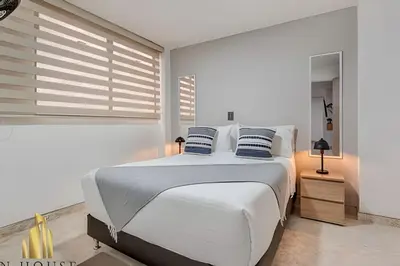 a white bedroom with a large white bed with blue pillows at Aria Living 302 - Modern and central in Laureles in Guayaquil