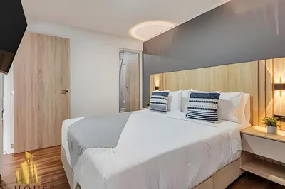 a bedroom with a large white bed with blue and white pillows at Aria Living 401 - Sophisticated Living in Laureles in Guayaquil
