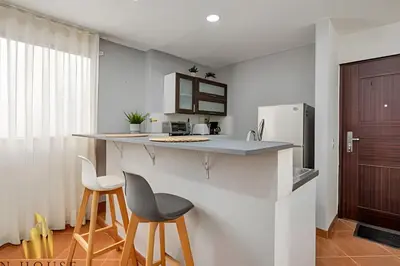 a kitchen with a counter and two stools and a refrigerator at Aria Living 500 - Modern with Private Terrace in Guayaquil