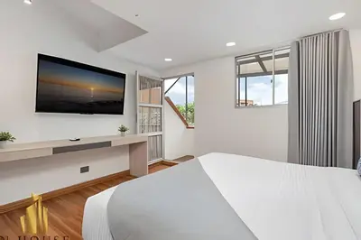a white bedroom with a large bed and a flat screen tv at Aria Living 501 - Design and Perfect Location in Guayaquil