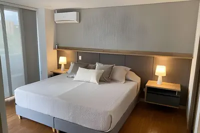 a bedroom with a large bed with two lamps at Campestre 605 - Cozy Studio with AC and Balcony in Envigado