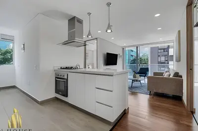 a kitchen with white cabinets and a living room at Campestre 704 - Sophisticated Apt with AC & gym in Envigado