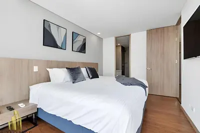 a bedroom with a large bed with white sheets at Campestre 704 - Sophisticated Apt with AC & gym in Envigado