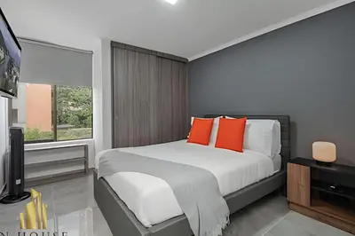 a bedroom with a bed with orange pillows and a television at Caracolí 301 - Donde el Estilo Grita Libertad in El Poblado