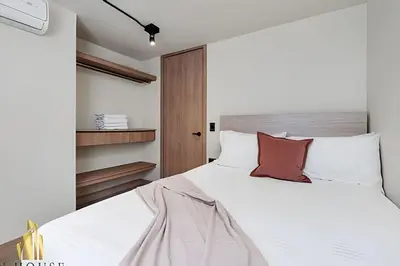 a bedroom with a large white bed with red pillows at Casa Solei 12-7 - Bright & Chic Apt in Manila / AC in El Poblado