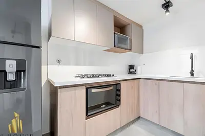a kitchen with wooden cabinets and a stove top oven at Casa Solei 12-9 - Stylish Apt with Jacuzzi & AC in El Poblado