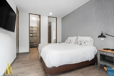 a bedroom with a white bed and a flat screen tv at Class Suites 202 - Colorful with Pool and gym in El Poblado