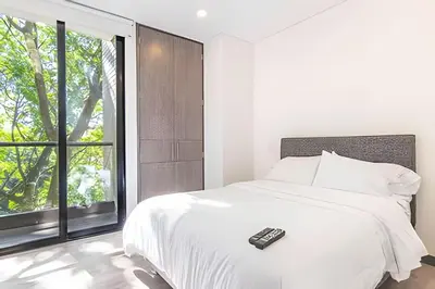 a bedroom with a bed with a remote control on it at Class Suites 502 - Modern Tranquility/Priv Balcony in El Poblado
