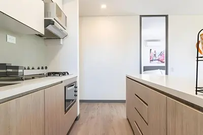 a kitchen with white counters and wooden cabinets at Class Suites 502 - Modern Tranquility/Priv Balcony in El Poblado