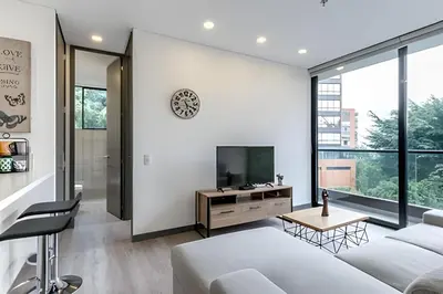 a living room with a bed and a tv at Class Suites 503 - Bright & Minimalistic Apt/Pool in El Poblado