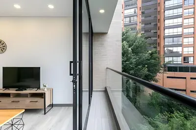 a living room with a sliding glass door and a television at Class Suites 503 - Bright & Minimalistic Apt/Pool in El Poblado