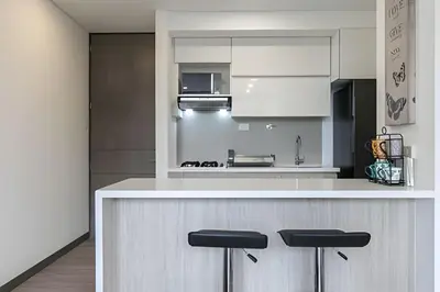 a kitchen with white cabinets and a counter with stools at Class Suites 503 - Bright & Minimalistic Apt/Pool in El Poblado