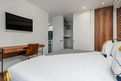 a bedroom with a bed and a desk and a television at Energy 403 - Prestigious Urban Oasis / Pool in El Poblado