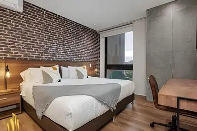 a bedroom with a large bed and a brick wall at Energy 403 - Prestigious Urban Oasis / Pool in El Poblado