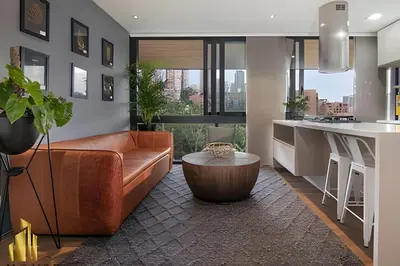 a living room with a brown couch and a kitchen at Energy 601 - Prestigious Apt/Pool & Jacuzzi in El Poblado