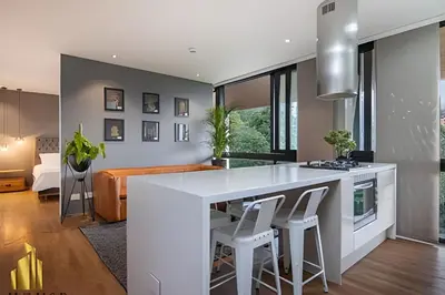 a kitchen and living room with a white counter and stools at Energy 601 - Prestigious Apt/Pool & Jacuzzi in El Poblado