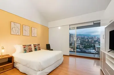 a bedroom with a white bed and a large window at Gauss 1205-Serenity Modern Apt/Terrace/Squash/Gym in El Poblado